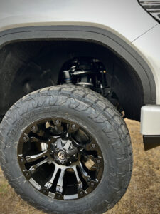Detailed view of the robust 35x12.50R20 TOYO AT3 tires and 20" custom wheels installed by Truxx Outfitters, illustrating superior grip and stability.