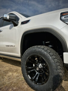 Detailed view of the robust 35x12.50R20 TOYO AT3 tires and 20" custom wheels installed by Truxx Outfitters, illustrating superior grip and stability