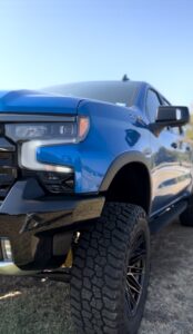 Frontal shot focusing on the headlight, offering a glimpse of the elevated proportions and enhanced stance of the 2023 Chevy 1500 ZR2 from the front to the back, showcasing the seamless integration of modifications by TRUXX Outfitters.