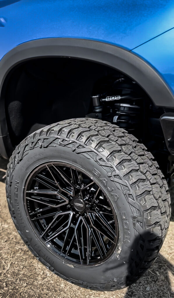 Close-up shot showcasing the intricate details of the Vossen HF6-5 Tinted Gloss Black 20X10 wheel paired with the rugged M/T Baja BOSS A/T 35-12.5R20 tire on the 2023 Chevy 1500 ZR2.