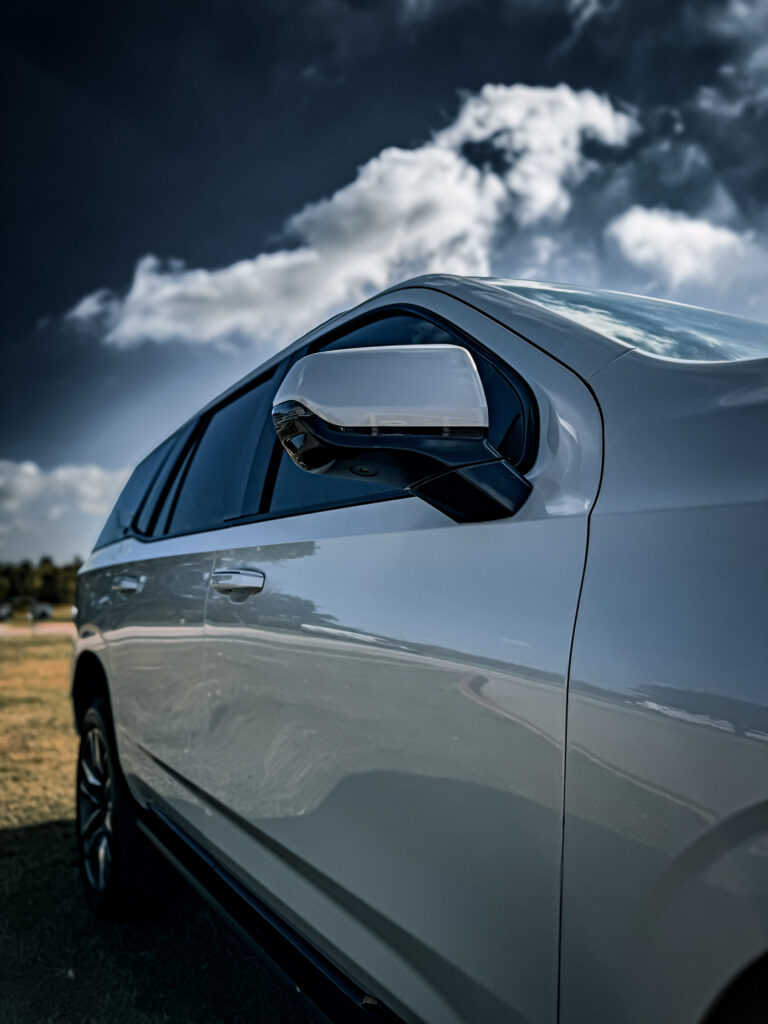 Side view of the 2024 Cadillac Escalade showcasing the blacked-out side mirror and window trim, highlighting TRUXX Outfitters' chrome delete work